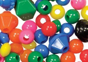 A close up photo of Opaque Beads. This close up photo shows that the beads come in bold colors such as pink, orange, blue, red, green, and yellow and also come in different shapes including spherical and diamond.