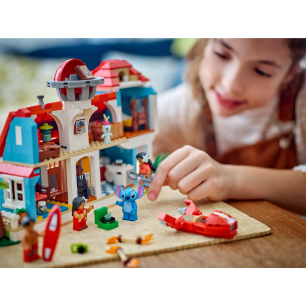 A young caucasian girl playing with LEGO Disney's Lilo and Stitch Beach House playset.